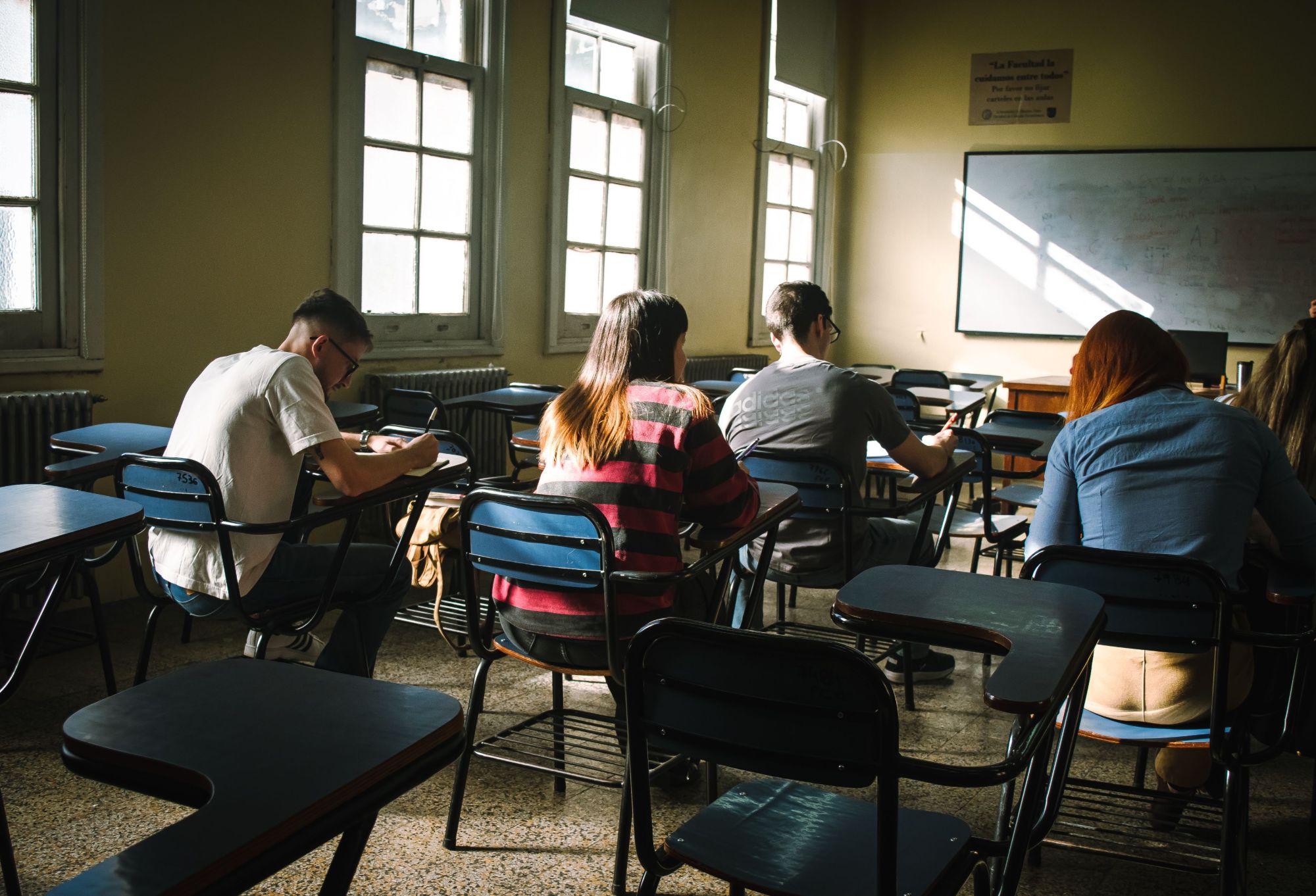 Alunos sentados nas carteiras de uma sala de aula, a escrever numa prova
